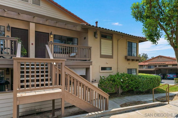 Front view of a two-story residential building with wooden stairs and balconies.