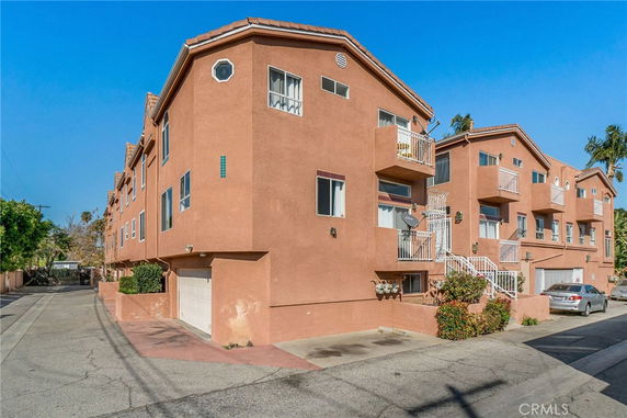 Front view of a multi-story apartment building with balconies and garages.