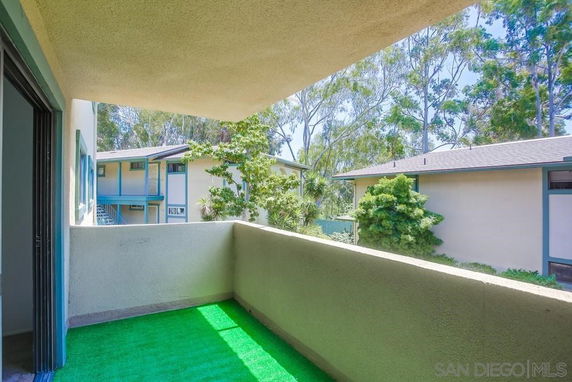 View from a balcony looking out at nearby residential buildings and trees.