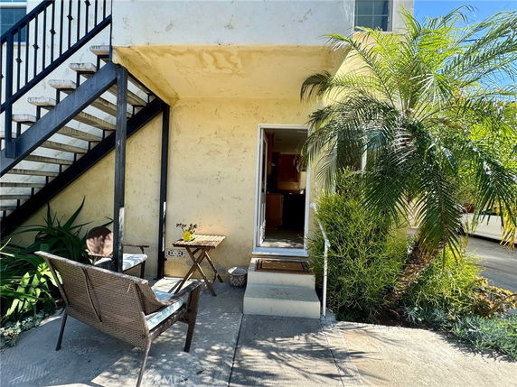 Side view of a house entrance with outdoor seating and staircase.