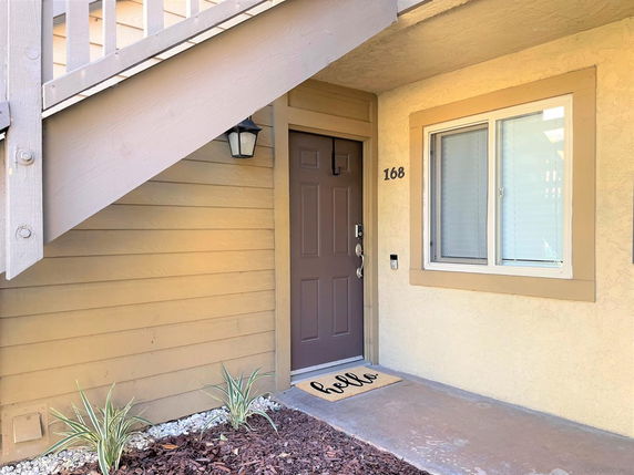 Front view of a house entrance with a staircase and a brown door.