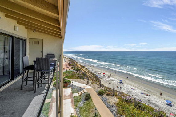 Ocean view from a balcony overlooking the beach with patio furniture.