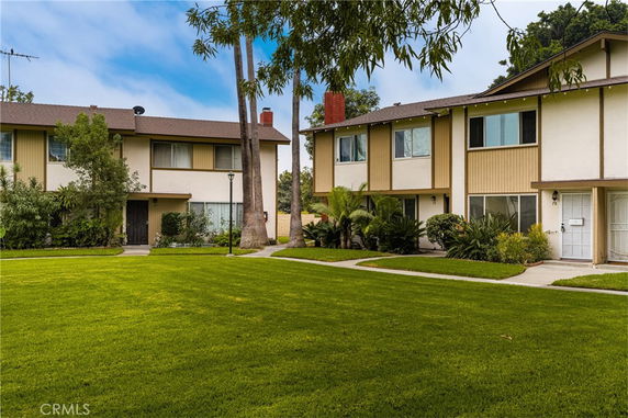Front view of multi-story residential buildings with a grassy lawn and trees.