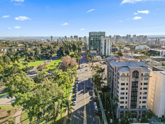 Panoramic view of a cityscape with a road, buildings, and a park.
