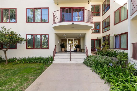 Front view of a multi-story building with a balcony and numerous windows.
