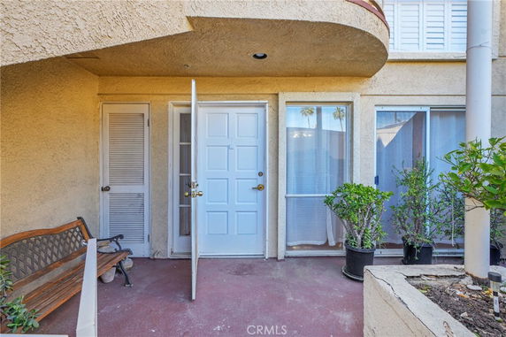 Front view of a house with a partially open door and a patio.