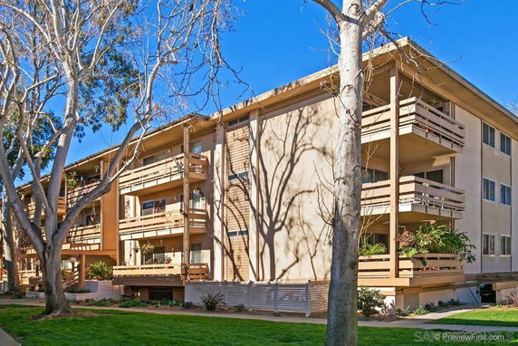 Front view of a multi-story apartment building with balconies and a flat roof.