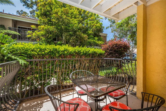 Outdoor patio area with iron table and chairs, surrounded by greenery.