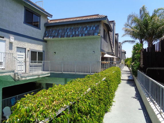 Front view of a multi-story residential building with a walkway and railing.