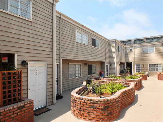 Front view of a two-story residential building with multiple entrances and brick planters.