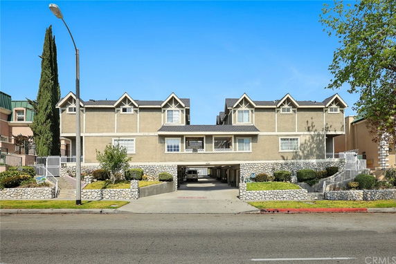Front view of a multi-story building with parking space underneath.