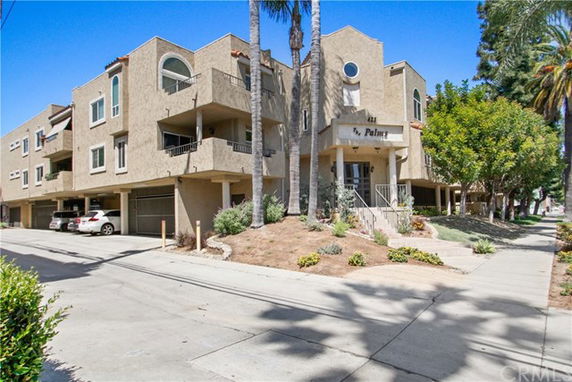 Front view of a multi-story residential building with balconies and an entrance stairway.