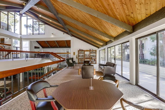 Interior of a recreational clubhouse with wooden ceiling and large windows.
