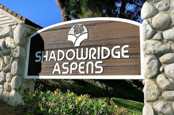 Sign for Shadowridge Aspens made of wood and surrounded by stone.