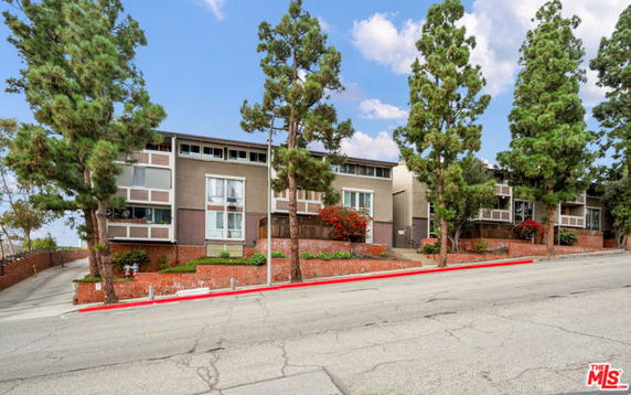 Front view of a multi-story building with large windows and a sloped driveway.