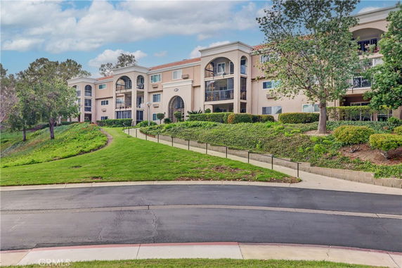 Front view of a multi-story building with balconies and arched entrances.