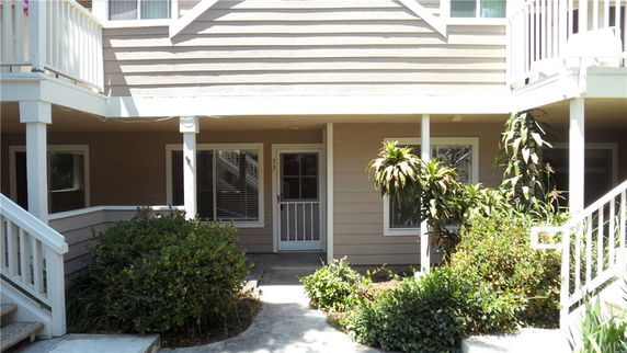 Front view of a two-story building with stairs and plants.
