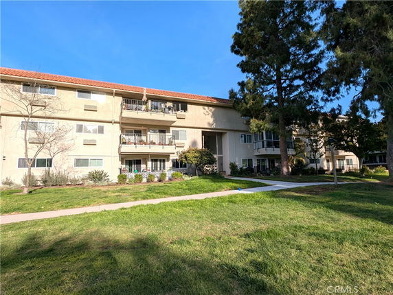 Front view of a multi-story residential building with balconies and a red-tiled roof.