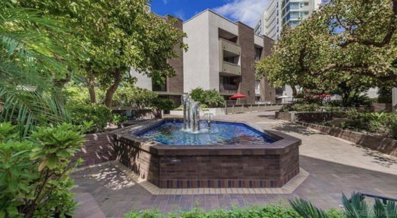 View of a residential building with a fountain and landscaped area.