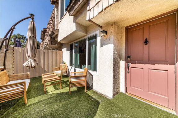 Front view of a house with a small patio area and pink door.