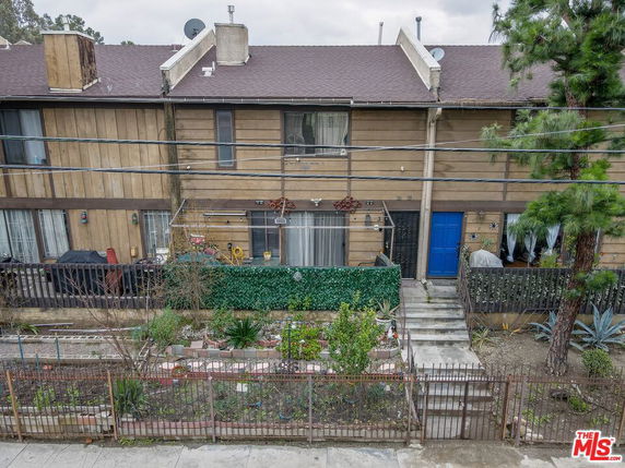 Front view of a multi-story townhouse with a garden and a blue door.