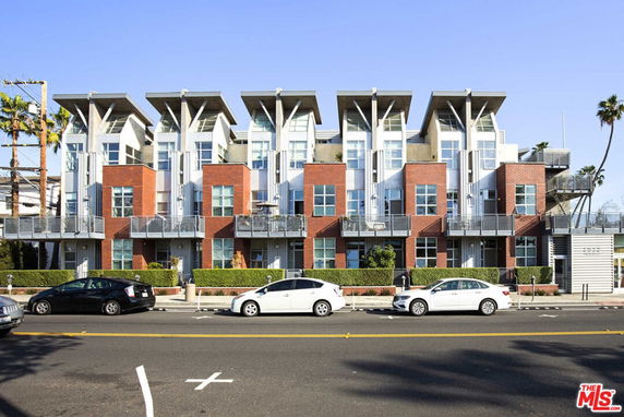 Front view of a modern multi-story building with angular roofs and balconies.