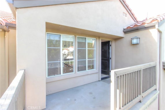 Front view of a house with light-colored exterior walls and a railing.