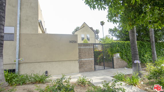 Front view of a house with a gated entrance and street address visible.