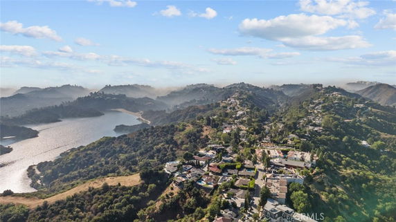 Panoramic view of hilly landscape with a lake and scattered houses.