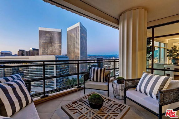 Balcony view overlooking skyscrapers and distant mountains.