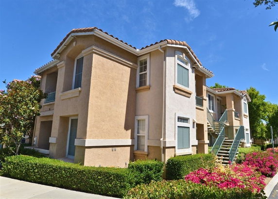 Front view of a two-story residential building with multiple units and stairs.