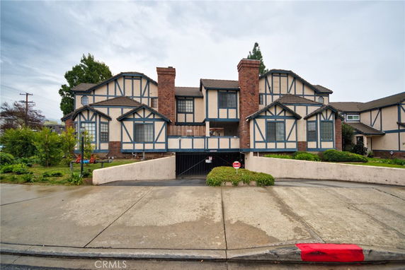 Front view of a multi-story house with a brick chimney and Tudor-style design.