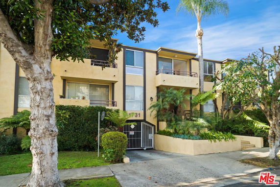 Front view of a multi-story building with balconies and a gated entrance.