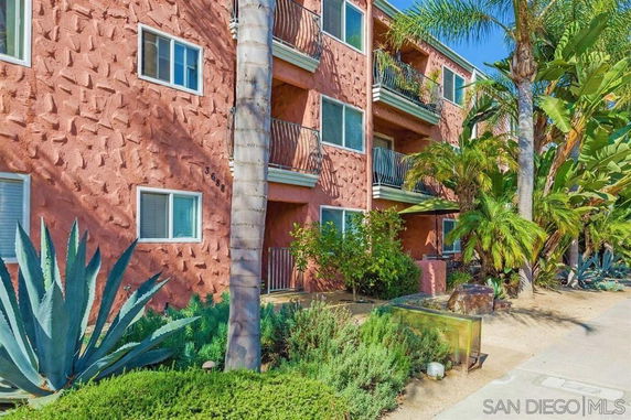 Front view of a multi-story apartment building with balconies and textured exterior walls.