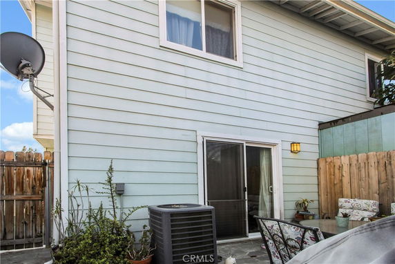 Side view of a two-story house with sliding glass door and satellite dish.