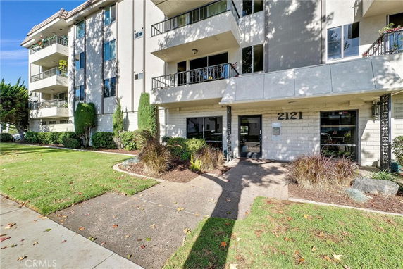 Front view of a multi-story apartment building with balconies and a main entrance.