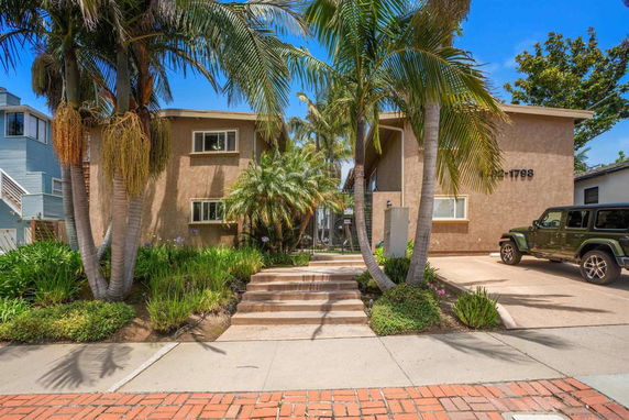 Front view of a two-story house with palm trees and a driveway.