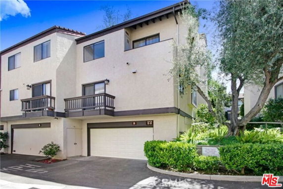 Front view of a multi-story house with balconies and a double garage.