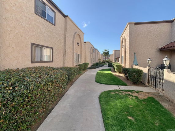 Front view of a row of two-story residential buildings with stucco walls and landscaped paths.