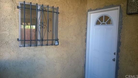Entryway of a house featuring a white door and a window with metal bars.