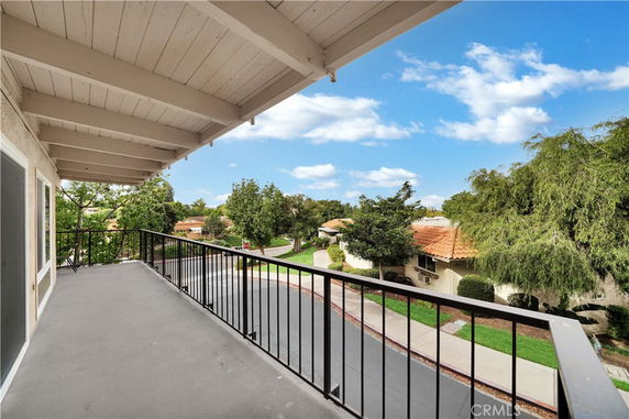 Balcony with railing overlooking a residential area with trees and houses.