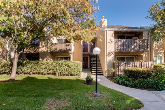 Front view of a two-story apartment building with balconies and a landscaped entrance.