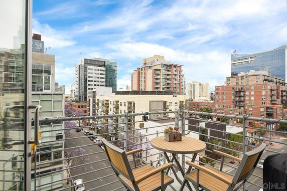 Panoramic view of city buildings from a balcony with a table and chairs.