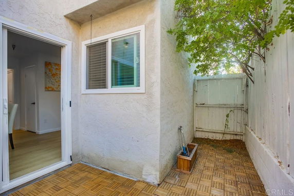 Outdoor corner with wooden tile flooring and a small window.