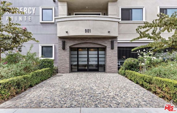 Front view of a multi-story building entrance with stone walkway and double door.