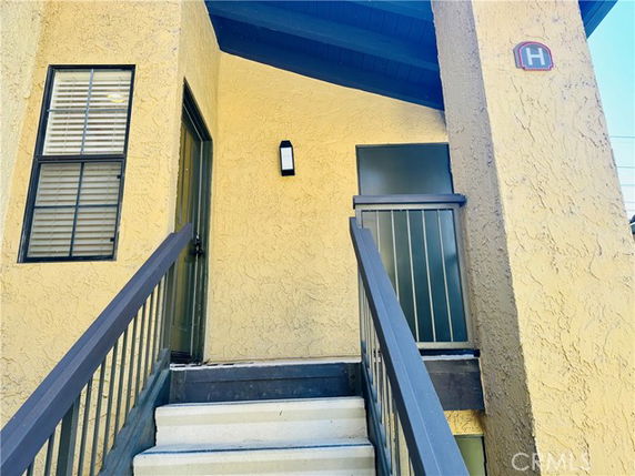Front entry view of a building with stairs leading to a door and a window.