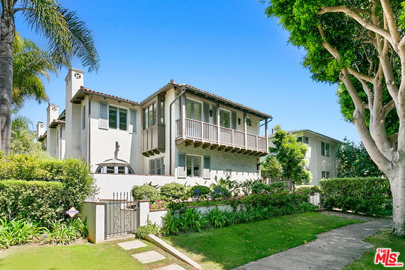 Front view of a multi-story house with balconies and a gated entrance.