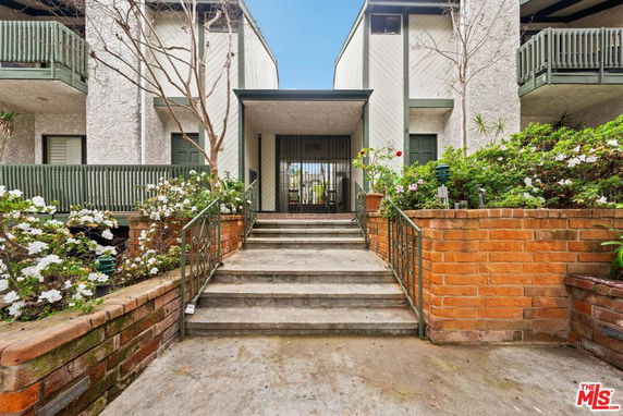Front view of a multi-story residential building with a central entryway and balconies.