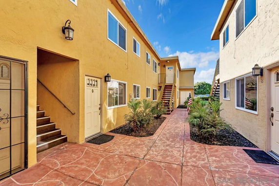 Outdoor walkway view of a residential building with multiple entrances and stairs.