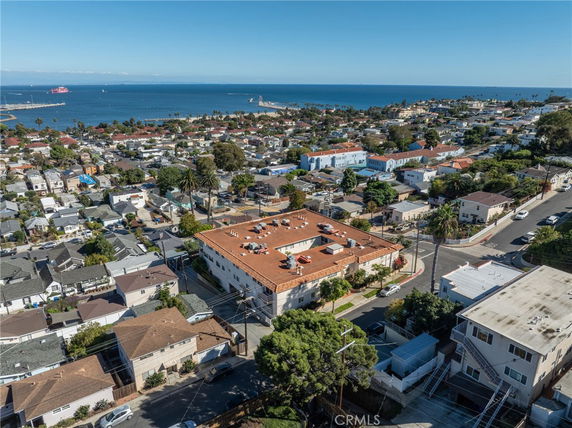 Aerial view of a coastal residential area with a large building in the foreground and the ocean in the background.